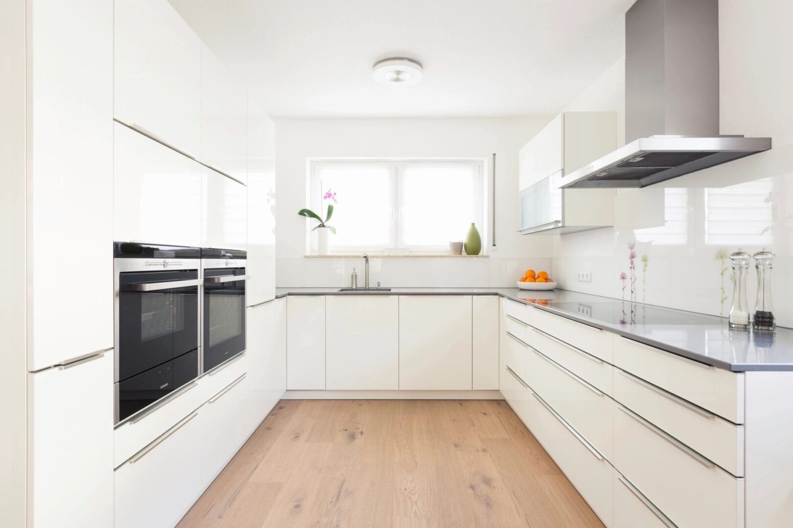 A kitchen with white cabinets and wood floors.