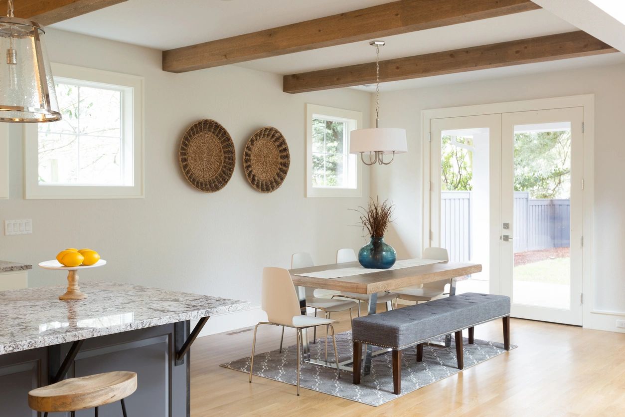 A dining room with wooden beams and white walls.